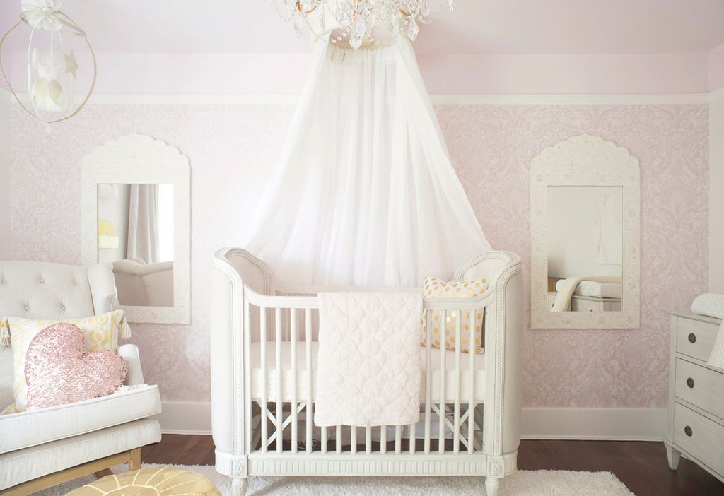 Princess theme bedroom for a girl with white canopy crib and pink wallpaper