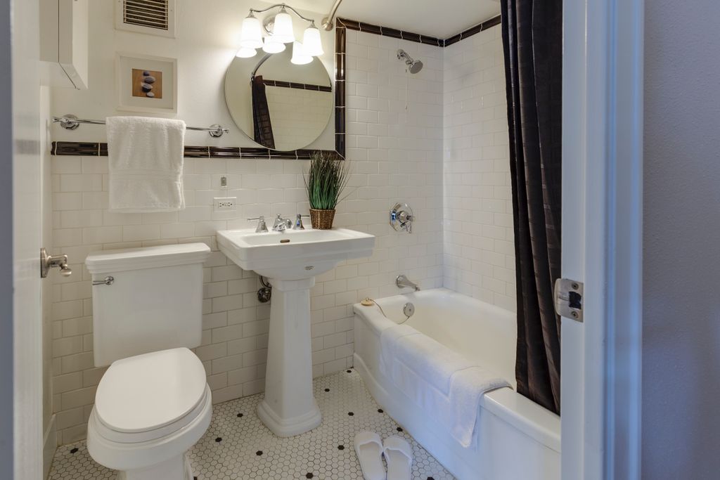White pedestal sink with round mirror and bathtub