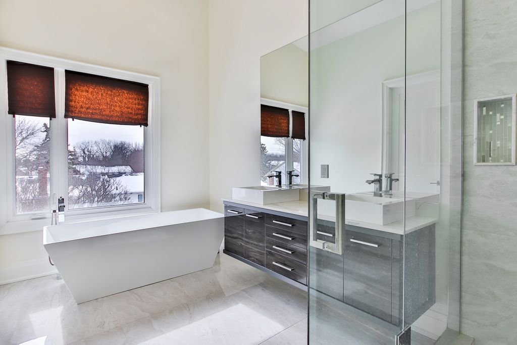 White bathroom with big frameless mirror and white bathtub 