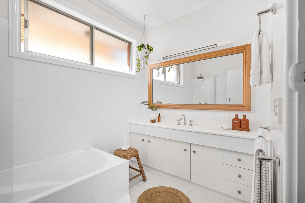 White bathroom with tub, vanity and candles