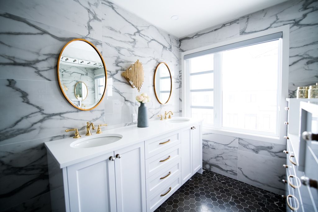 Bathroom with marble walling and white cabinets 