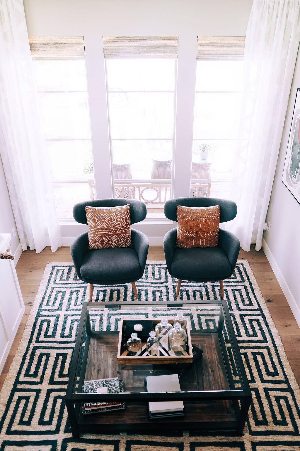 Living room with black and white design rug, two grey chairs and glass coffee table