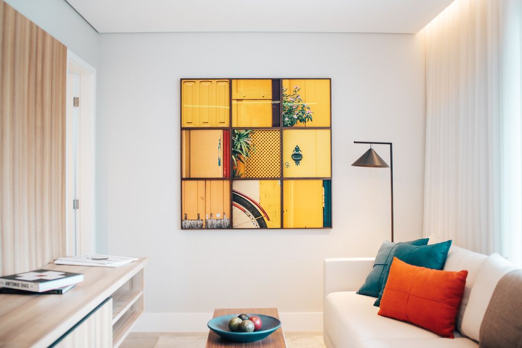 Living room with white couch, yellow toned wall paintings and colourful throw pillows