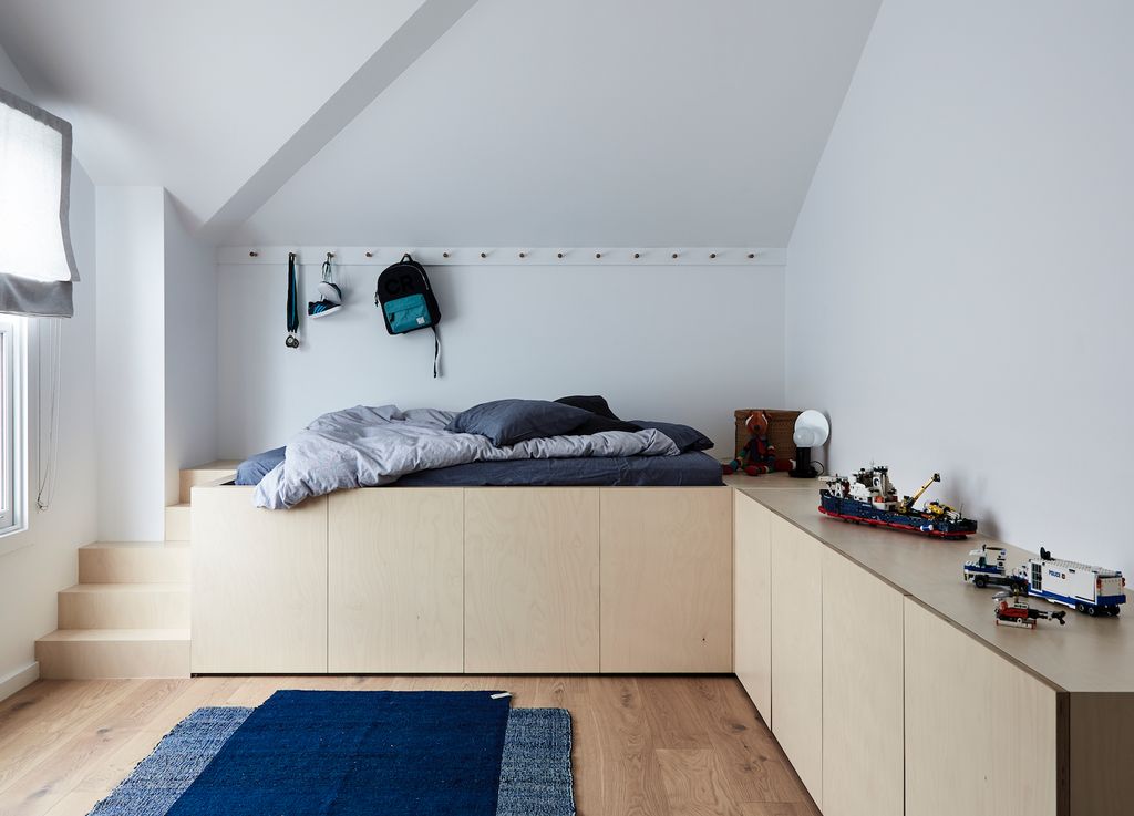 Minimal kids room with storage space under bed and blue rug