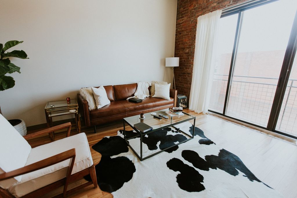 Living room with brown leather couch and cow skin rug