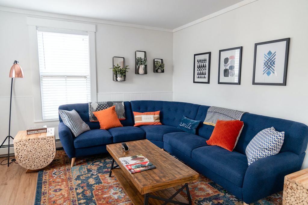 Blue sectional couch with white walls and wooden furniture 
