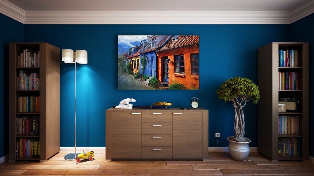 Blue accent living room wall with wooden cabinets and wall art