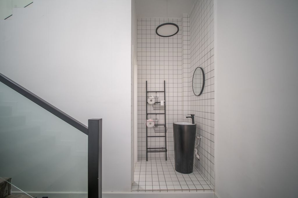 White and grey bathroom with black sink and storage ladder