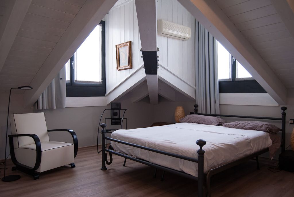 Bedroom with overhead beams and simple mattress cover on iron bed