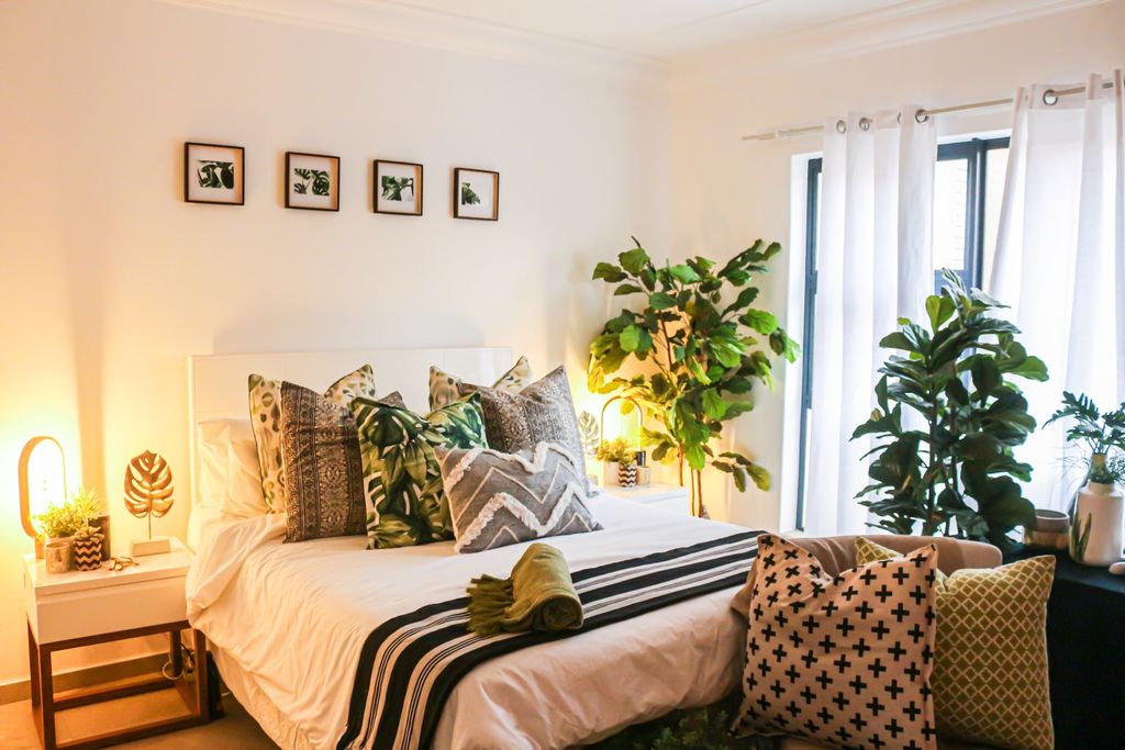 Bedroom with big potted green plants around the window area