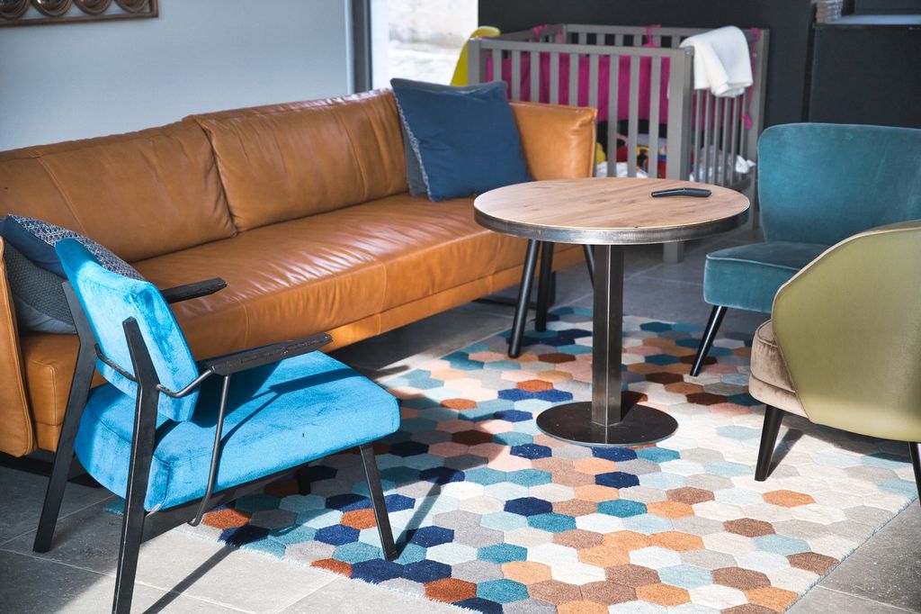 Living room with brown leather couch, turquoise chairs and colourful honeycomb rug