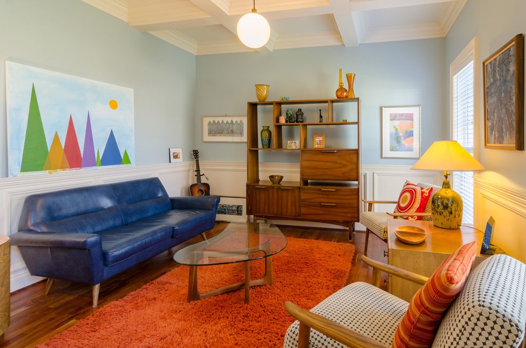 Living room with blue leather couch, paintings and mismatch furniture 