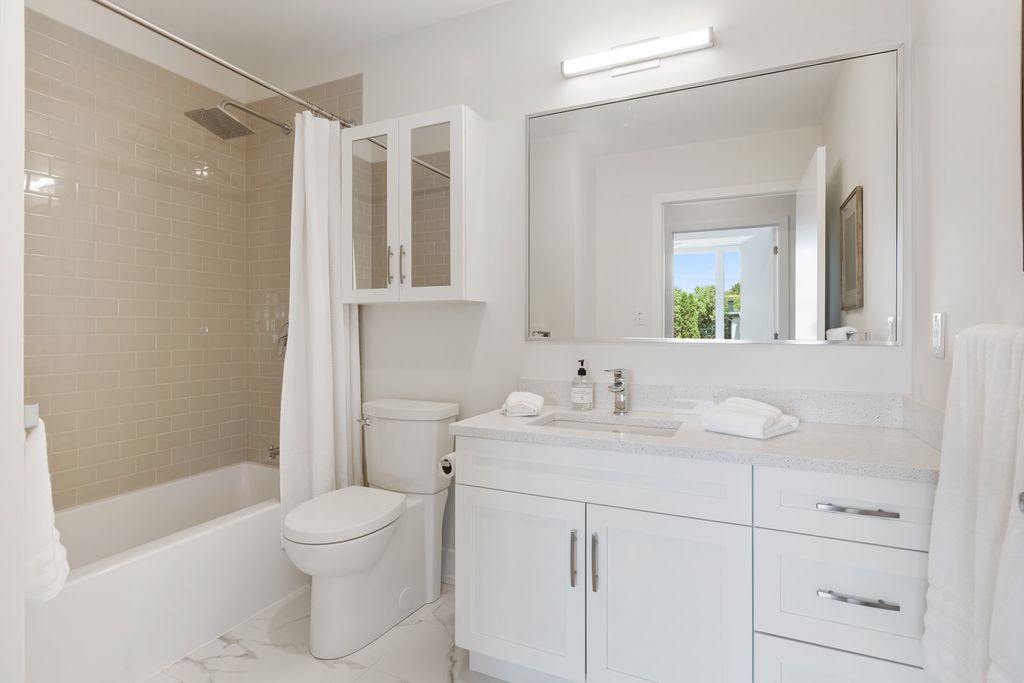 White bathroom with spacious cabinets and bathtub with curtain 