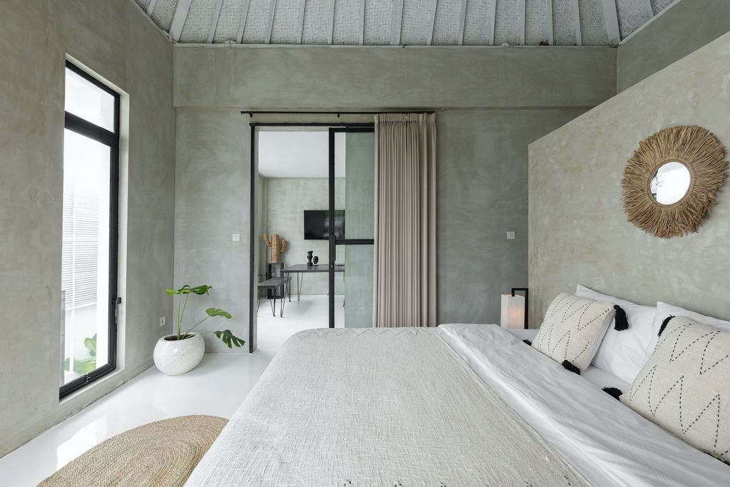 Grey bedroom with mirror behind the bed and plant in white pot