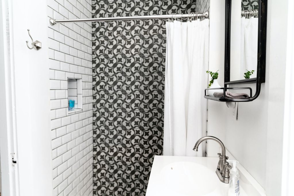 White bathroom with black tile shower and curtains 