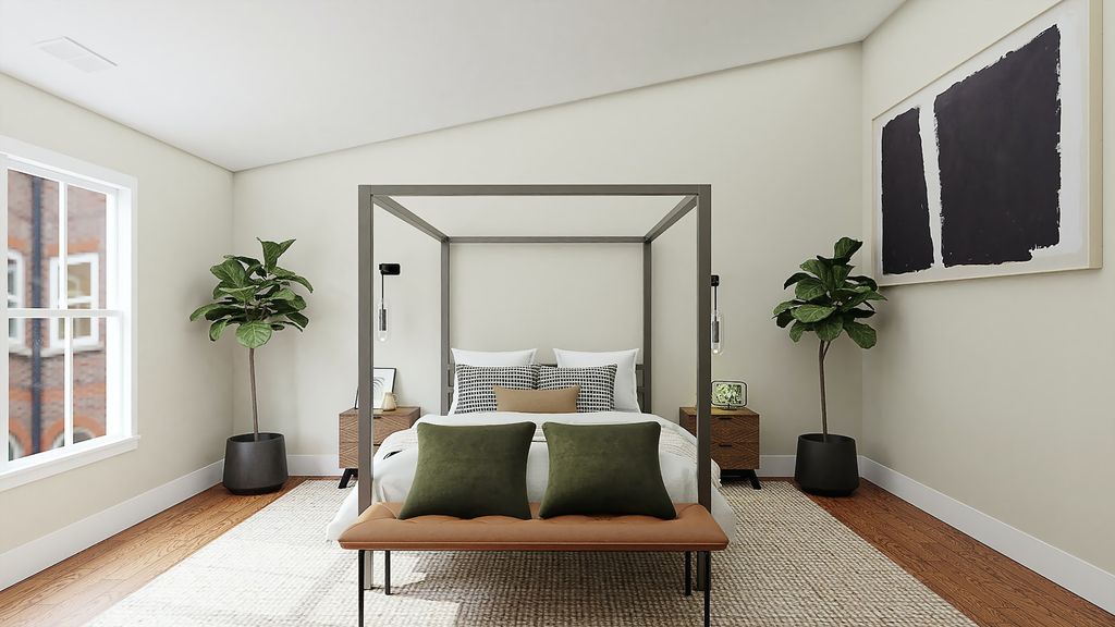 Canopy bed with green pillows and potted plants on either side of bed